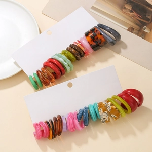 Gros plan de boucles d'oreilles créoles colorées en résine et acrylique sur table beige