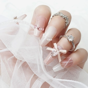 Sparkly handmade press-on nails in pink and white with pearls and ribbon bows