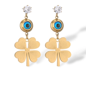 Detailed view of gold earrings with blue evil eye and clover pendants with crystal studs