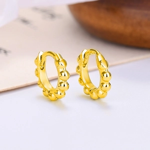 Macro shot of gold beaded hoop earrings with polished finish and secure snap closure