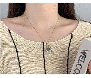 Close-up of a double-sided black heart pendant necklace on a gold S925 silver chain