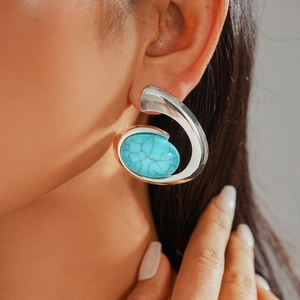 Detailed close-up of chunky silver spiral earring with a large oval turquoise stone inlay