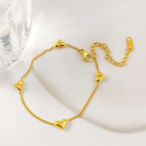Elegant gold heart bracelet with sparkling zircons on a white ceramic display stand