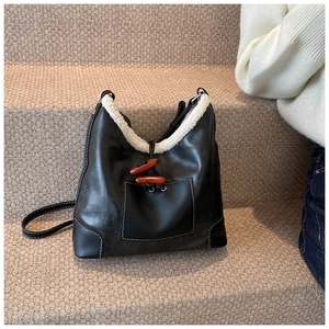 Close-up of retro black tote bag with white faux fur trim and wooden toggle buttons