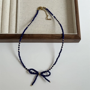 Detailed shot of dark blue faceted bead necklace with a handcrafted bow pendant