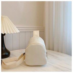 Close-up of cream fabric kids chest bag with adjustable strap and metal zipper detail