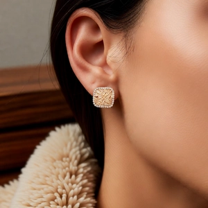 Close-up of elegant gold rhombus stud earrings with pavé zircons on model's ear