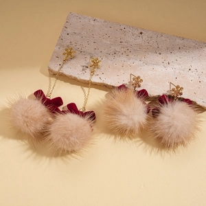 Vintage gold snowflake earrings with beige pom poms and burgundy velvet bows on stone