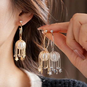 Détail de boucles d'oreilles perles avec glands étoiles en finitions or et argent