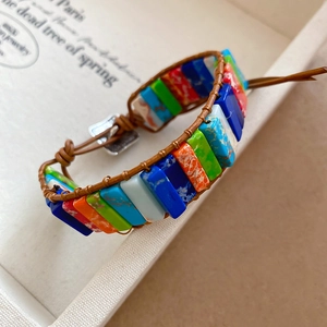 Détail de perles en pierre colorées tissées à la main avec cordon en cuir marron