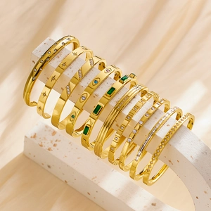 Set of ten assorted gold-plated stainless steel bangles on minimalist stone display