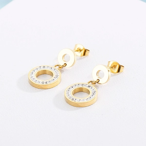 Close-up of golden double circle earrings featuring sparkling crystals on a textured surface