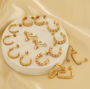 Close-up of luxury 18k gold-plated earrings with pavé zircons and white enamel bow details