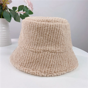 Close-up of thick beige lamb wool bucket hat texture on a white decorative table