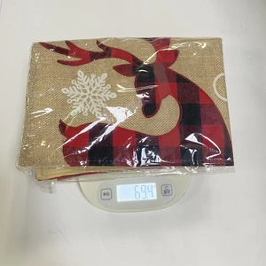 Détail d'un set de table en toile de jute avec renne en écossais rouge et flocons brodés