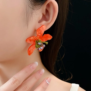 Detail of vintage flower earrings with orange crystals worn on a model ear