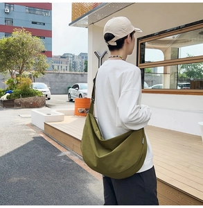 Outdoor shot of the olive green oxford fabric crossbody bag showing its large capacity