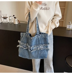 Détail du grand sac cabas en denim bleu avec franges effet usé et broderie blanche
