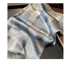 Dettaglio di un foulard in seta grigio-blu con eleganti motivi a quadri e astratti