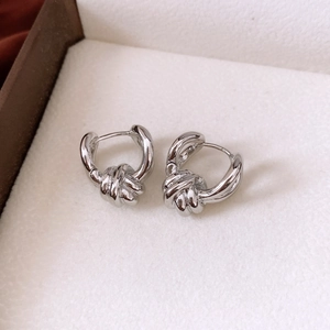 Detail shot of silver twisted knot hoop earrings featuring a polished metallic finish