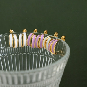 Double layer C-shaped enamel hoop earrings in white and lavender on a glass rim