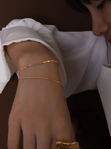 Detail of 18K gold-plated double-layer blade and snake chain bracelets on wrist