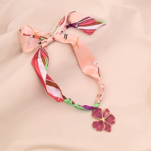Detailed view of the purple flower enamel pendant with a pink silk scarf necklace.