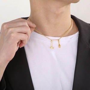 Detail of man wearing golden mini hammer and wrench tool pendants on a slim chain necklace