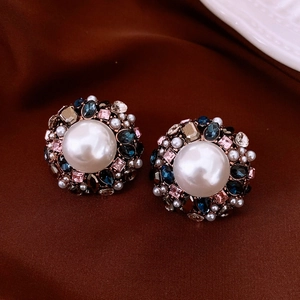 Detail of vintage baroque pearl earrings with colorful rhinestones on brown velvet