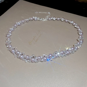 Close-up of elegant rose pearl necklace with sparkling zircons on a wavy silver chain