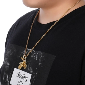 Close-up of a iced-out gold motorcycle pendant necklace worn by a male model