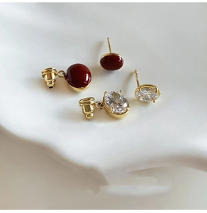 Detail von 14K vergoldeten Ohrringen mit dunkelrotem Stein und klarem ovalem Zirkonia