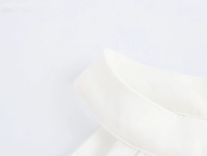 Nahaufnahme des eleganten Neckholder-Ausschnitts dieses weißen Perlen-Netzkleides aus Baumwolle