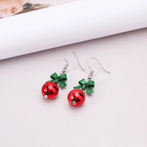 Christmas bow earrings with festive red beads and green glitter on a white surface