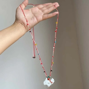 Detailed close-up of handmade bohemian long necklace with colorful beads and white resin dog pendant