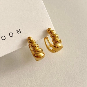 Macro shot of gold spiral hoop earrings with croissant texture on a white display card