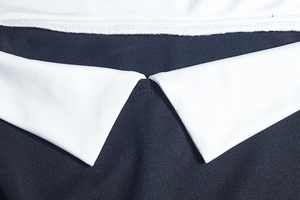 Dettaglio ravvicinato del colletto a contrasto bianco e nero con cuciture di precisione