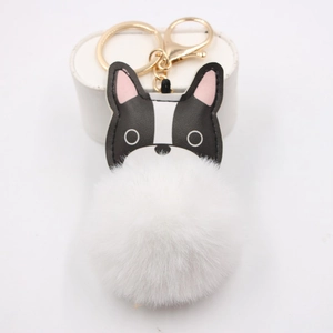 Detail of a white fluffy pompom keychain with a black and white French Bulldog charm