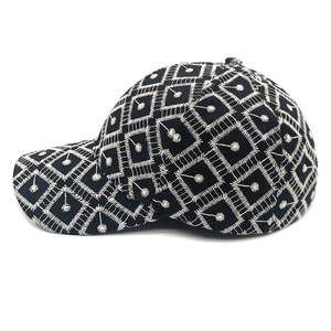 Detail of black baseball cap featuring intricate white diamond embroidery and twill texture