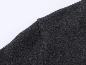 Macro shot of dark grey wool knit fabric texture and shoulder seam on a cardigan