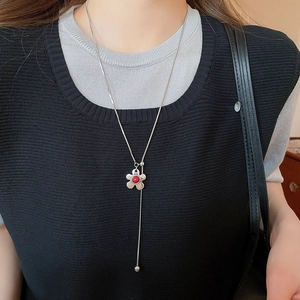 Detail of silver snake chain with a red flower slider on a black knit top