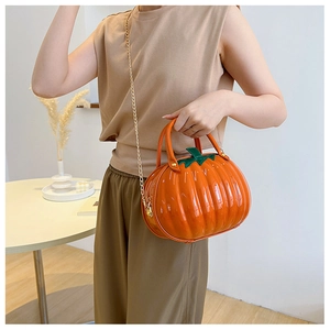 Chic pumpkin crossbody bag with gold chain strap shown on a model in a cozy room