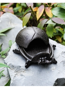 Detail of vintage cast iron ladybug key box showing the hollow interior on a natural rock