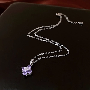 Detailed close-up of a silver floral pendant with purple zircon stones on a leather base