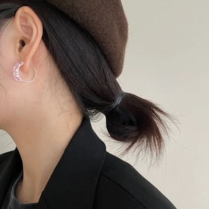 Detail of pink zircon C-shaped silver earring worn by model in minimalist fashion style