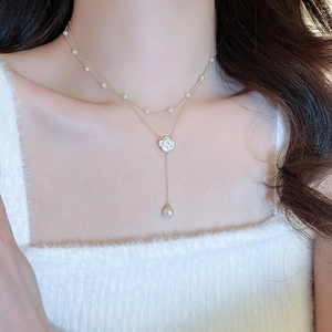 Close-up of elegant double-layered gold necklace with white camellia and pearls on neck