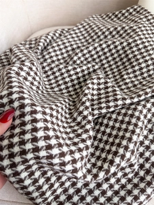Detail of soft brown and white houndstooth cashmere fabric texture held by a hand