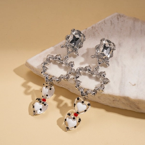 Détail de boucles d'oreilles cœur en argent avec pois noirs et cristaux clairs