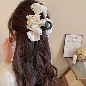 Polka dot bow claw clip shown on long wavy hair with vintage silk texture detail