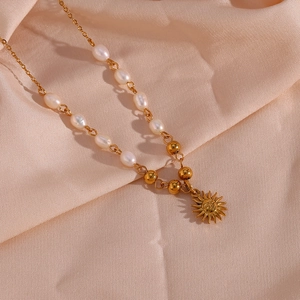 Detailed view of a gold sun pendant necklace with pearls on a silk fabric background